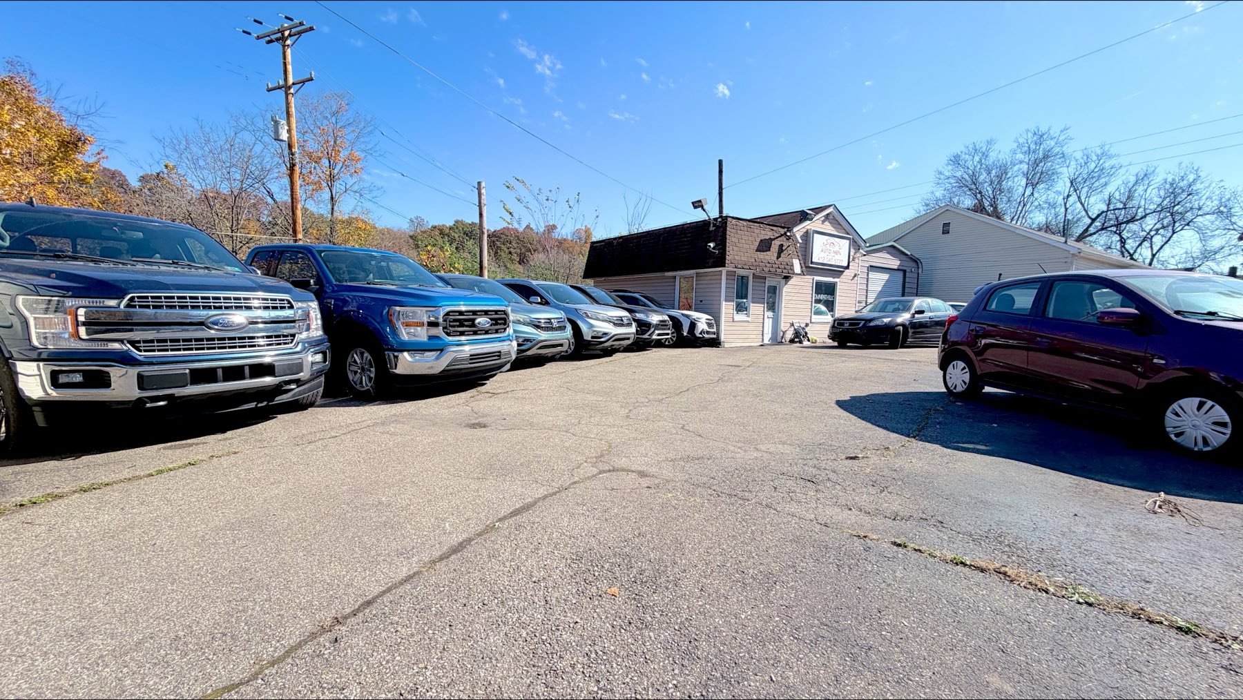 The Auto-Men lot at 1170 Milltown Rd, with trucks and SUVs lined up in front of the office